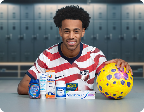 Soccer player Tyler Adams poses in a locker room with a ball and several Haleon products. A U.S. Soccer Logo reads Official Partner of U.S. Soccer, and a disclaimer reads Some products may contain NSAIDs and/or Acetaminophen and should not be taken together. Please review labels and use as directed.